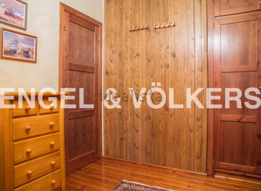 Charming bedroom with built-in wooden wardrobes and chest of drawers.