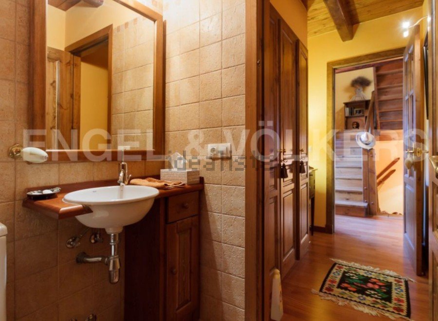Rustic bathroom with wooden vanity and tiled walls.