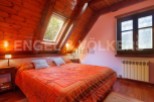 Cozy attic bedroom with wooden beams and skylights, offering abundant natural light.
