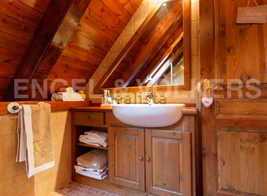Charming wooden bathroom with a unique sloped ceiling and built-in vanity.