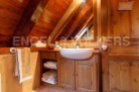 Charming wooden bathroom with a unique sloped ceiling and built-in vanity.