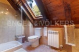 Charming attic bathroom with skylight, wooden beams, and tiled walls.