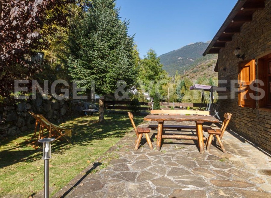 This charming mountain cabin boasts a rustic wooden patio set, perfect for outdoor dining and relaxation.