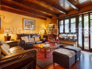 Cozy living room with wooden beams, leather sofas, and large windows offering abundant natural light.