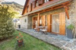 Charming stone house with wooden accents and a cozy patio, perfect for enjoying the mountain views.