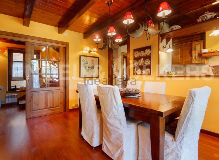 Rustic dining room with wooden beams, hardwood floors, and a large wooden table.