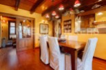 Rustic dining room with wooden beams, hardwood floors, and a large wooden table.