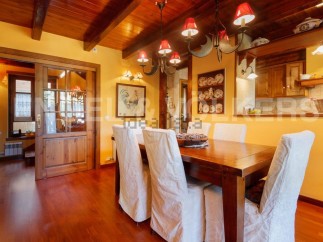Rustic dining room with wooden beams, hardwood floors, and a large wooden table.