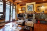 Cozy mountain chalet with a stone fireplace, hardwood floors, and large windows offering scenic views.
