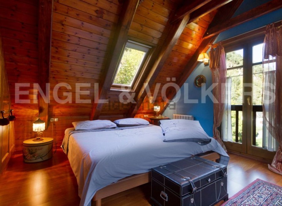 Cozy attic bedroom with wooden beams, skylight, and stunning views.