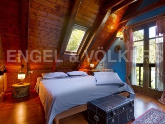 Cozy attic bedroom with wooden beams, skylight, and stunning views.