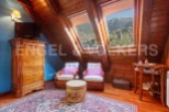 Charming attic bedroom with wooden beams, skylights offering mountain views, and a cozy sitting area.