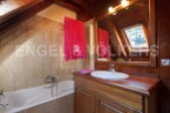 Charming attic bathroom with wooden beams, a bathtub, and a vanity with a wooden countertop.