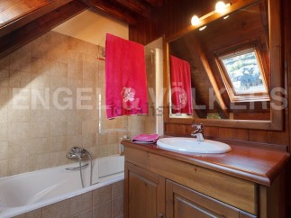 Charming attic bathroom with wooden beams, a bathtub, and a vanity with a wooden countertop.
