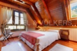 Cozy attic bedroom with wooden beams and large windows offering stunning views.