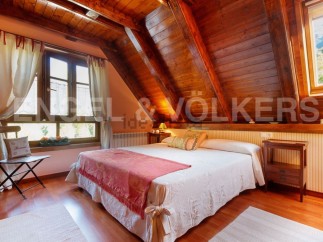 Cozy attic bedroom with wooden beams and large windows offering stunning views.