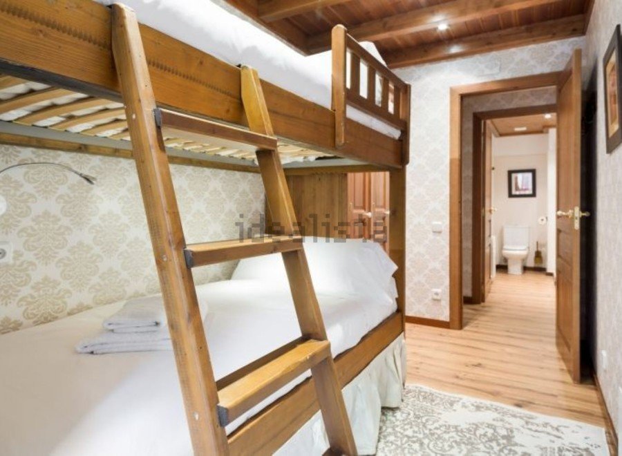 Cozy bunk beds in a charming room with wooden accents and elegant wallpaper.