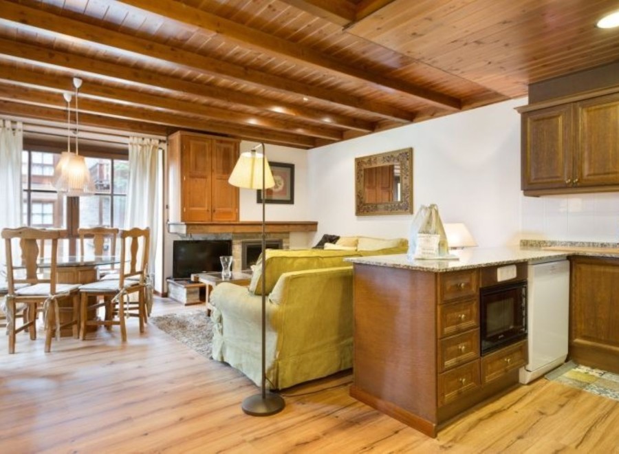 This charming apartment boasts a spacious living area with hardwood floors and a cozy wood-beamed ceiling.