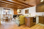 This charming apartment boasts a spacious living area with hardwood floors and a cozy wood-beamed ceiling.