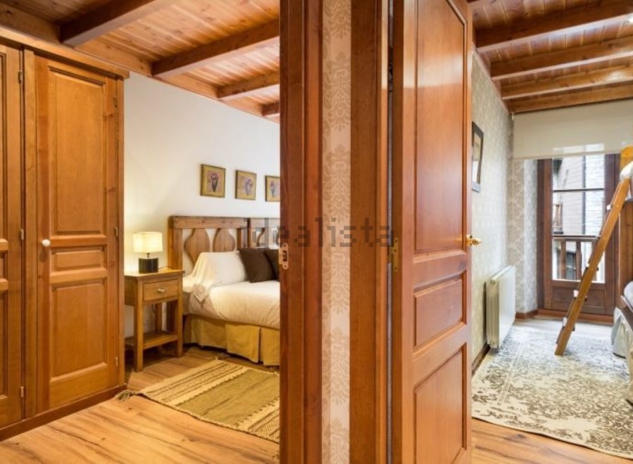 Charming wooden apartment with a cozy bedroom and a bunk bed in a second room.