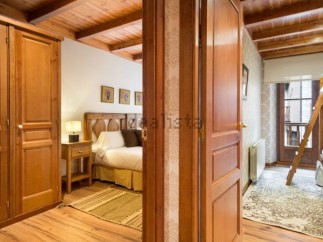 Charming wooden apartment with a cozy bedroom and a bunk bed in a second room.