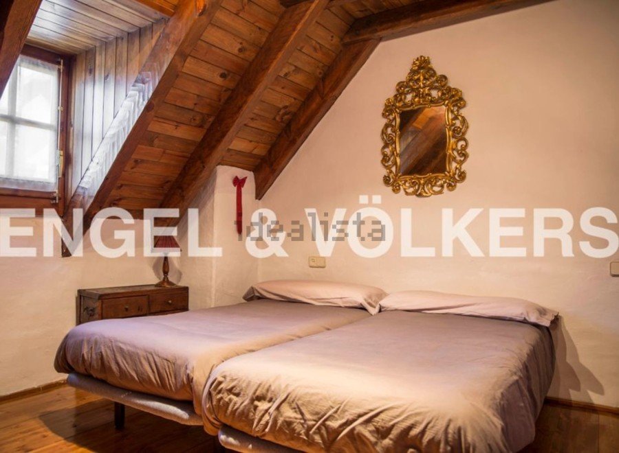 Charming attic bedroom with wooden beams and sloped ceilings.