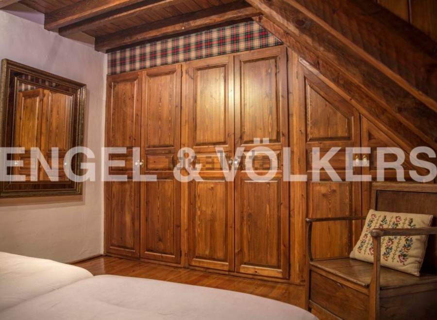 Charming rustic bedroom with built-in wooden wardrobes and beamed ceiling.