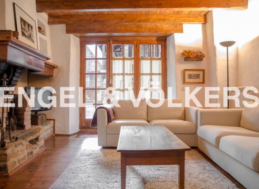 Charming rustic apartment featuring exposed wooden beams, a cozy fireplace, and large windows offering ample natural light.