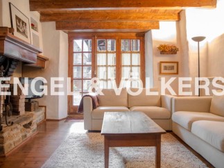 Charming rustic apartment featuring exposed wooden beams, a cozy fireplace, and large windows offering ample natural light.