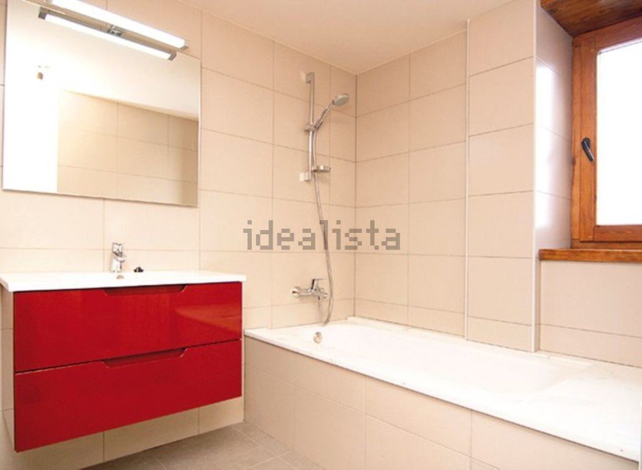 Modern bathroom with red vanity and built-in bathtub.
