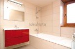 Modern bathroom with red vanity and built-in bathtub.