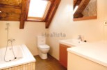 Charming attic bathroom with wooden beams, skylight, and modern fixtures.
