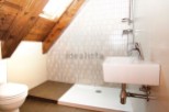 Charming attic bathroom with wooden beams, skylight, and modern fixtures.