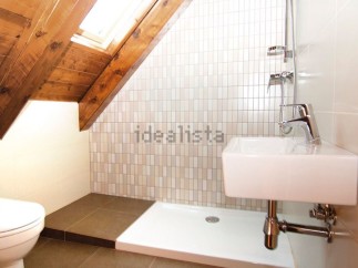 Charming attic bathroom with wooden beams, skylight, and modern fixtures.