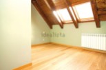 Bright attic room with wooden beams and skylights.