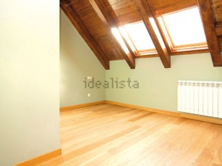 Bright attic room with wooden beams and skylights.