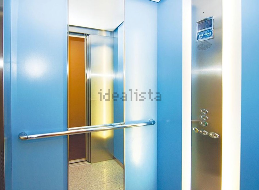 Modern elevator with sleek stainless steel and light blue walls.