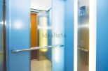 Modern elevator with sleek stainless steel and light blue walls.