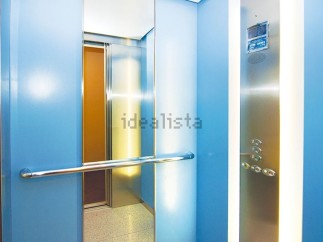 Modern elevator with sleek stainless steel and light blue walls.