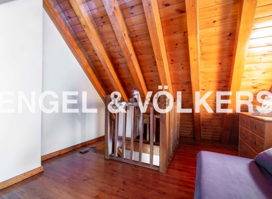 Discover this stunning attic space featuring exposed wooden beams and a charming wooden staircase.