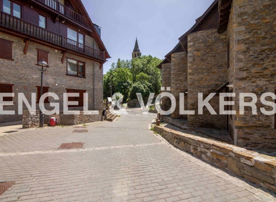 Charming stone buildings line a quaint cobblestone street, creating a picturesque village setting.