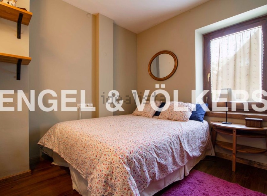 Cozy bedroom with floral bedding, wooden floors, and a rustic wooden side table.