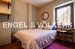 Cozy bedroom with floral bedding, wooden floors, and a rustic wooden side table.
