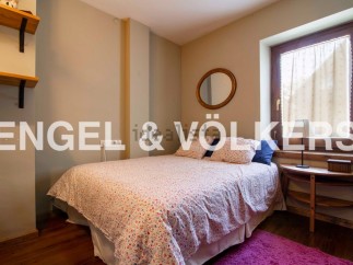Cozy bedroom with floral bedding, wooden floors, and a rustic wooden side table.
