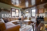 Cozy living room with wooden ceiling and large windows offering ample natural light.