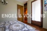 This charming bedroom boasts a cozy and elegant atmosphere, featuring a comfortable bed with a beautiful patterned duvet and a wooden door leading to a spacious closet.