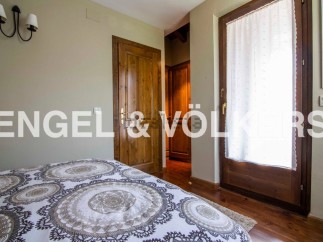 This charming bedroom boasts a cozy and elegant atmosphere, featuring a comfortable bed with a beautiful patterned duvet and a wooden door leading to a spacious closet.