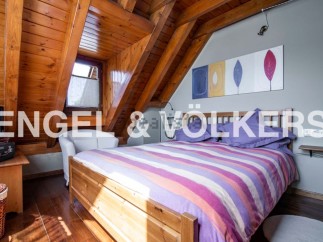 Charming attic bedroom with wooden beams and striped bedding.