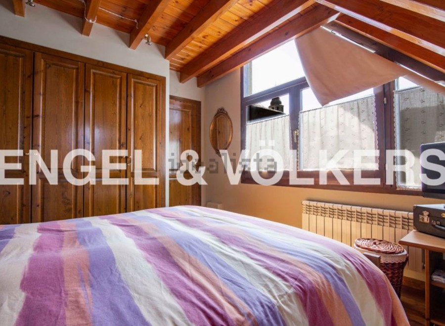 Charming attic bedroom with wooden beams and built-in wardrobe.
