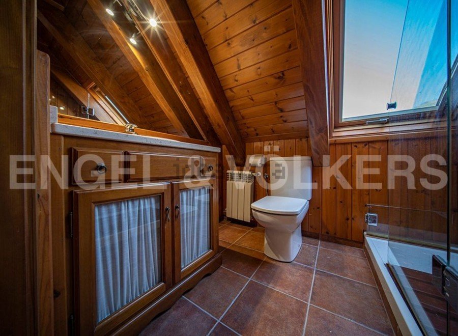 Charming attic bathroom with wooden beams, tiled floor, and a walk-in shower.
